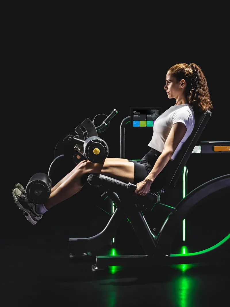 Athlete mid-rep on the Leg Extension/Curl, lit in green